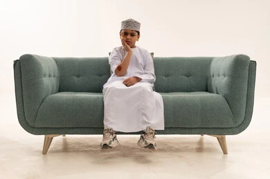 طفل عماني يعاني من ألم الأسنان على الأريكة