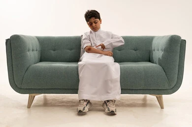 Saudi Boy with Arm Injury on Green Sofa
