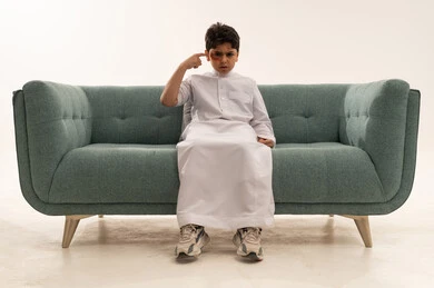 طفل سعودي بالثوب على أريكة مع كدمة عين