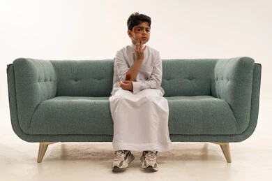 Injured Saudi Boy with Facial Bruising on Sofa