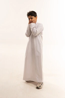 طفل سعودي بالثوب التقليدي أمام خلفية بيضاء