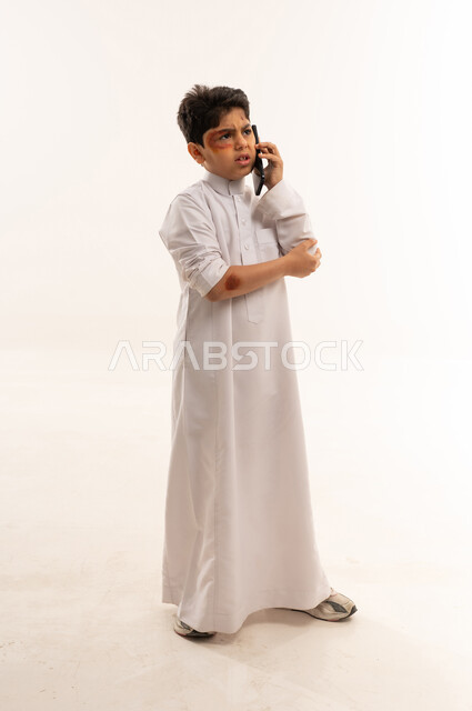 Saudi Boy in Thobe Talking on Phone with Bruises