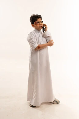 Saudi Boy in Thobe Talking on Phone with Bruises