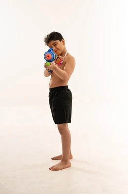 طفل سعودي يوجه مسدس ماء على خلفية بيضاء