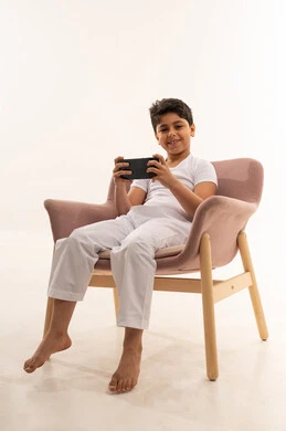 Saudi Boy Using Smartphone in Pink Armchair