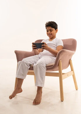 طفل عربي يجلس على كرسي يستخدم هاتف ذكي