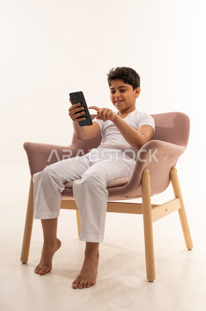 Arab Boy Using Smartphone on Pink Armchair