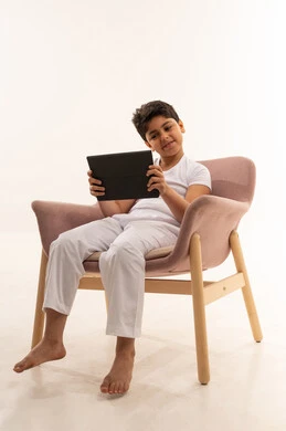 طفل عربي يستخدم جهاز لوحي على كرسي استوديو