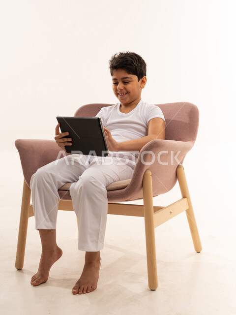 Arab Boy Using Digital Tablet in Pink Armchair