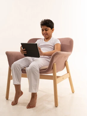 طفل عربي يستخدم جهاز لوحي على كرسي وردي