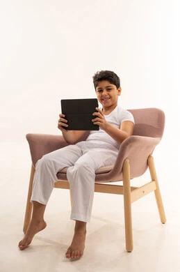 Saudi Boy Using Digital Tablet in Pink Armchair