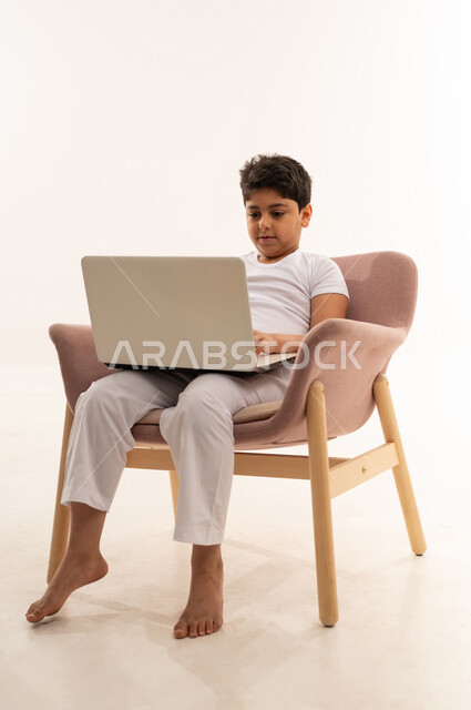 Saudi Boy Using Laptop in Modern Armchair