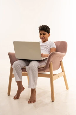 Saudi Boy Using Laptop in Armchair White Background