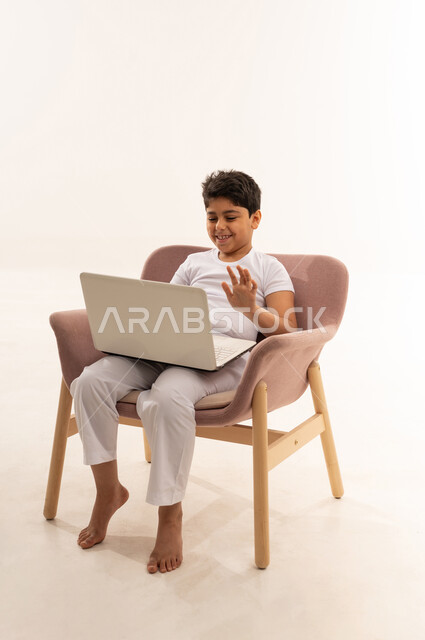 Arab Boy Waving at Laptop in Pink Armchair