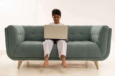 Saudi Boy Using Laptop on Modern Sofa