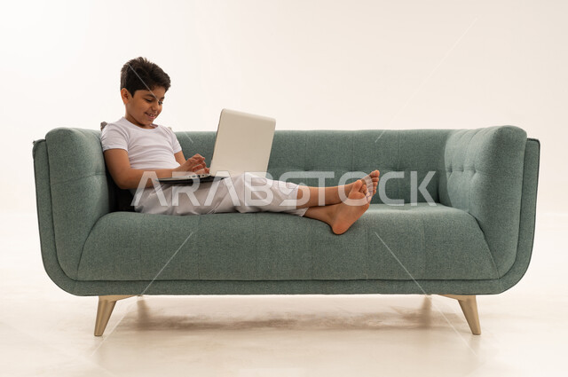 Arab Boy Using Laptop on Green Sofa White Background