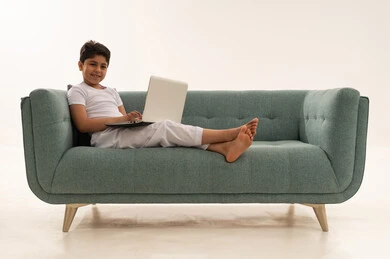 Arab Boy Using Laptop on Teal Sofa Studio Shot