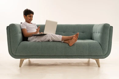 طفل عربي يستخدم المحمول على أريكة فيروزية