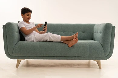 Arab Boy Using Smartphone on Modern Green Sofa
