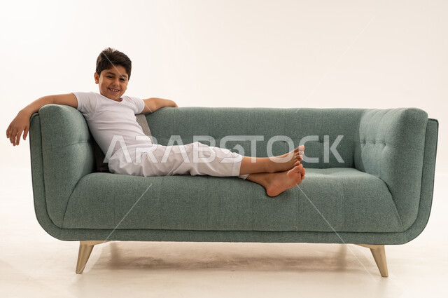 Saudi Boy Relaxing on Green Sofa White Background