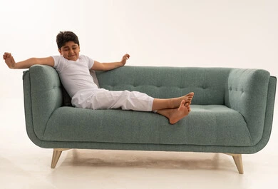 طفل سعودي يتمدد على أريكة فيروزية حديثة