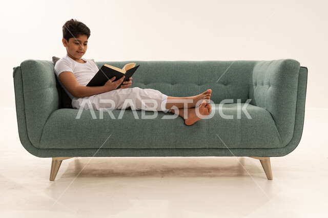 Saudi Boy Reading a Book on Modern Sofa