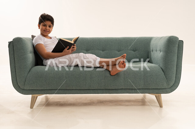 Saudi Boy Reading Book on Modern Teal Sofa