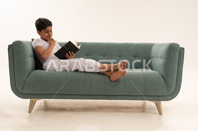 Arab Boy Reading Book on Turquoise Sofa