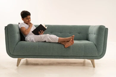 طفل عربي يقرأ كتاباً على أريكة فيروزية