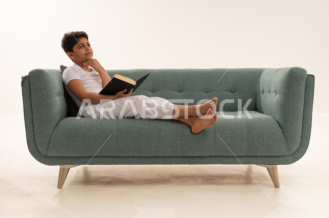 Saudi Boy Reading and Thinking on Sofa