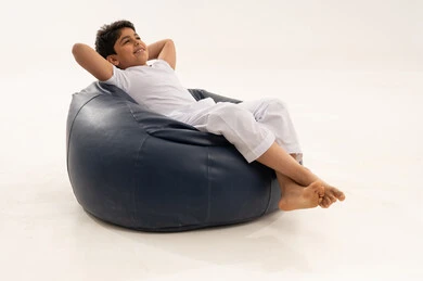 طفل سعودي يسترخي على كرسي بين باج أزرق