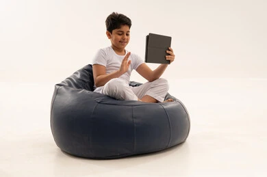 طفل عربي يلوح لجهاز لوحي على مقعد محشو أزرق