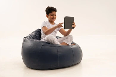 طفل عربي يستخدم جهاز لوحي على كرسي محشو