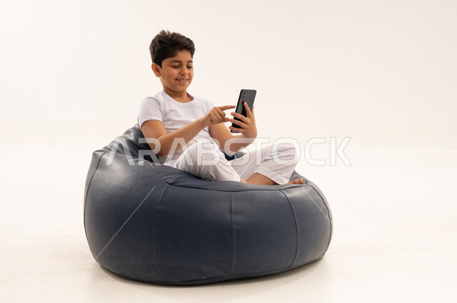 طفل سعودي يستخدم هاتف ذكي على مقعد أزرق