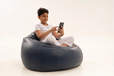 طفل سعودي يستخدم هاتف ذكي على مقعد أزرق