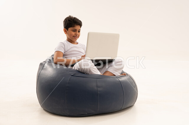 طفل سعودي يستخدم كمبيوتر محمول في الاستوديو