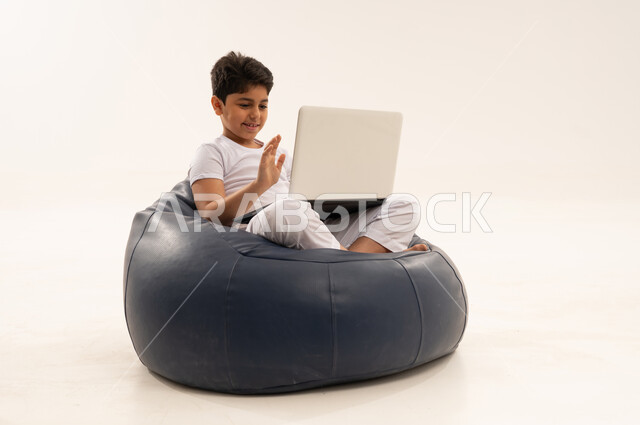 طفل عربي يستخدم المحمول على كرسي محشو