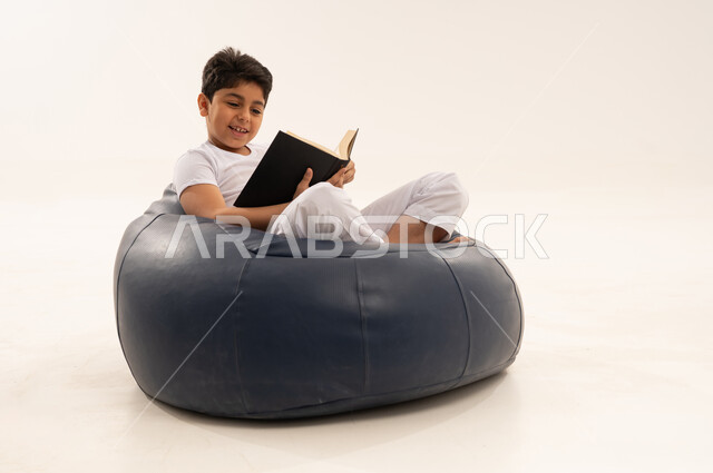طفل عربي يقرأ كتاباً على مقعد بين باج