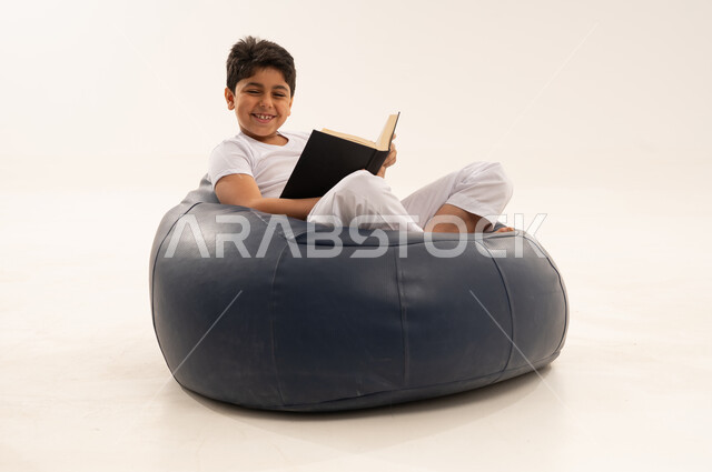 Arab Boy Reading Book on Blue Bean Bag Chair