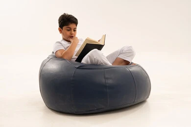 طفل سعودي يقرأ كتابا على مقعد مريح