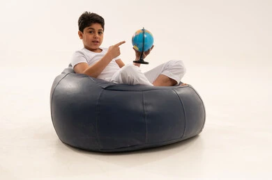 طفل عربي يحمل مجسم الكرة الأرضية على مقعد مريح في الاستوديو