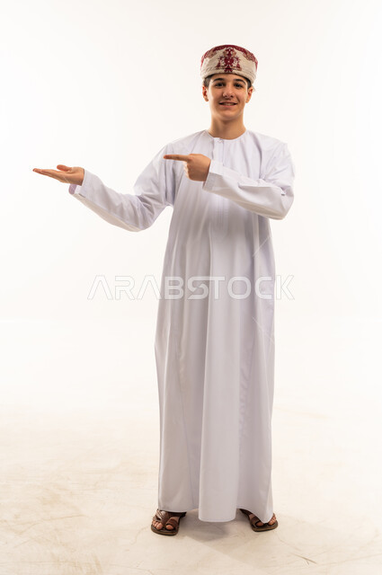 Omani Boy in Dishdasha Pointing at Hand on White Background