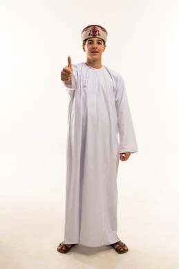 ولد عماني بالدشداشة التقليدية يشير بالإبهام
