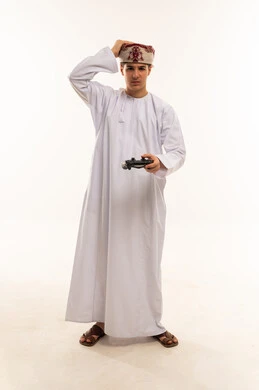 رجل عماني مع جهاز تحكم ألعاب بخلفية بيضاء