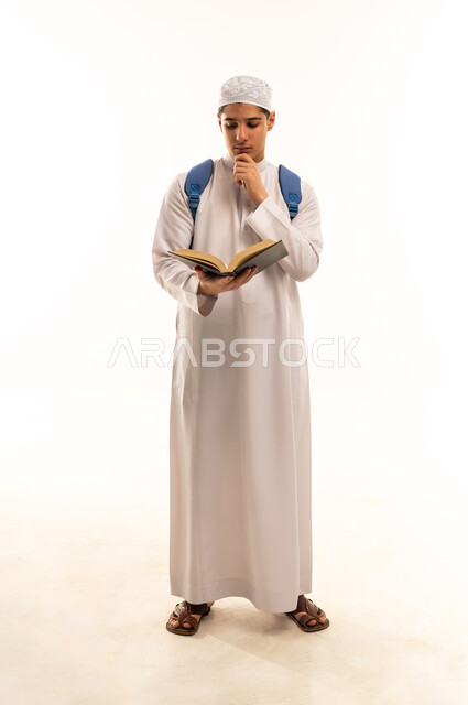 A Saudi student is reading a book against a white background.