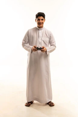 شاب عربي يرتدي الثوب مع جهاز تحكم ألعاب فيديو