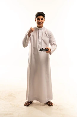 شاب سعودي يحمل جهاز تحكم ألعاب ويحتفل بالفوز