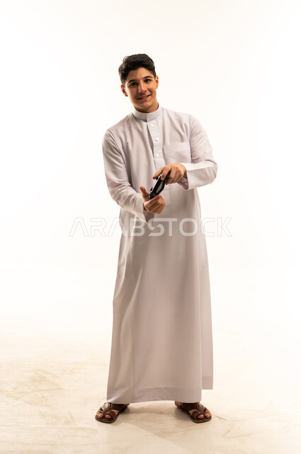 شاب سعودي بالثوب يحمل جهاز تحكم ألعاب