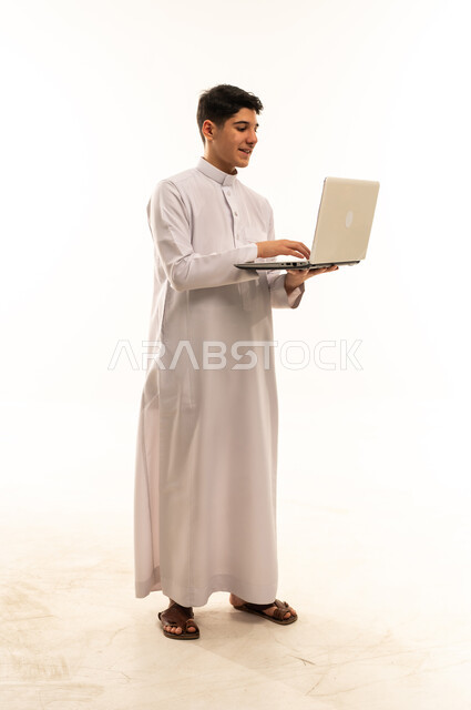 Saudi Teenage Boy in Traditional Thobe Using Laptop