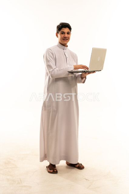 مراهق سعودي بالثوب التقليدي يحمل لابتوب